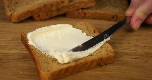 Butter Being Spread on Sliced Whole Wheat Bread