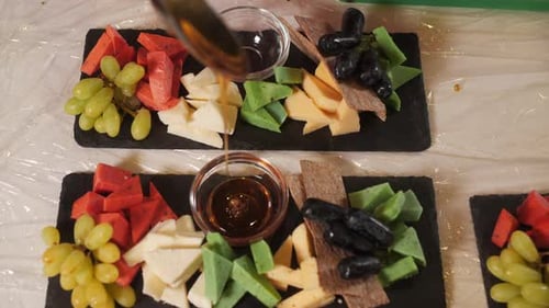 Chef Pouring Honey in Bowl Over Food Platter