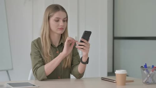 Young Woman Using Smartphone at Desk in Office