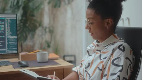 Female Programmer Writing Notes and Speaking with Colleague