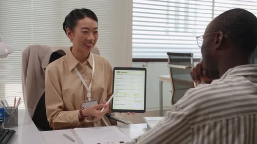 Woman Presents Business Information to Man in Office