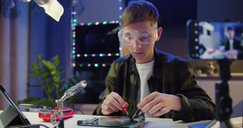 Un colegial caucásico con gafas y una herramienta repara un aparato Electrónico doméstico. Profesional masculino