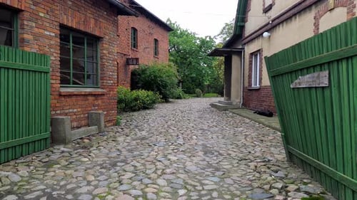 fliege in einen leeren Hinterhof, Steinpflaster, grüner Zaun, altes Gebäude