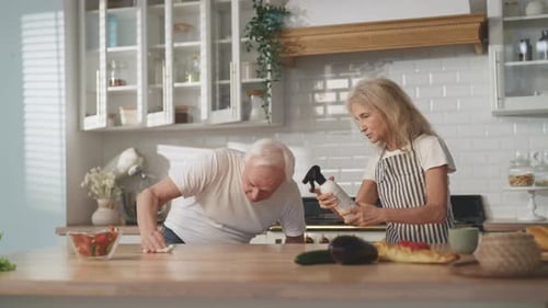 Senior Couple Cleaning Kitchen Together During Daytime