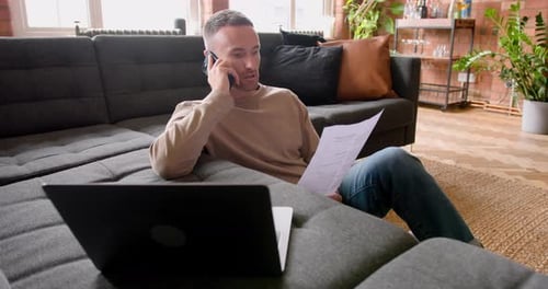 Man Working From Home on Couch Talking on Phone