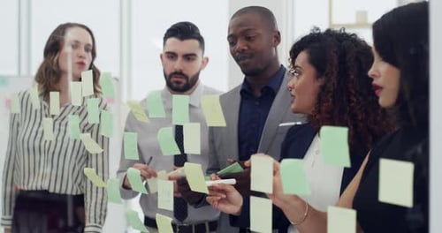 4k video footage of a group of businesspeople brainstorming with notes on a glass wall in an office