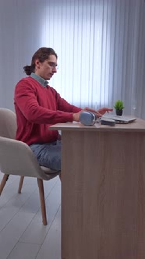 Young Adult Man Spending Time at Home Man Student Sits at Desk Works on Computer Finishing Studying