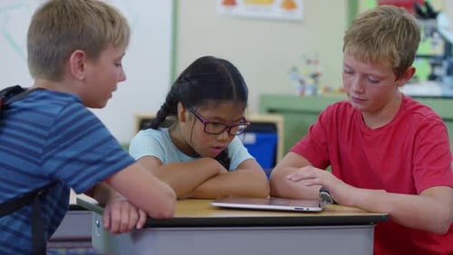 Elementary school students learning together using digital tablets in class