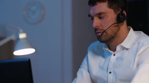 Man Working Late with Headset at Computer