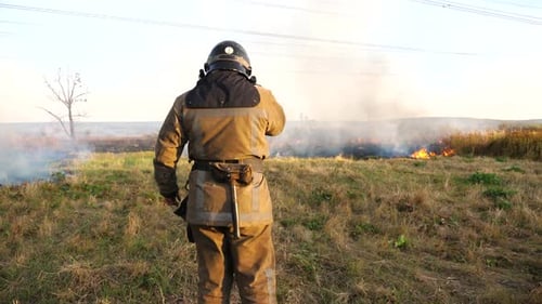 Professional Fireman in Full Equipment Talking on Walkietalkie on Place at Fire Near a Big Red Truck