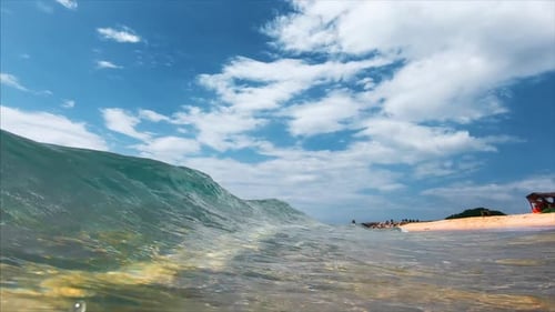 Ocean wave breaks over the sandy tropical beach