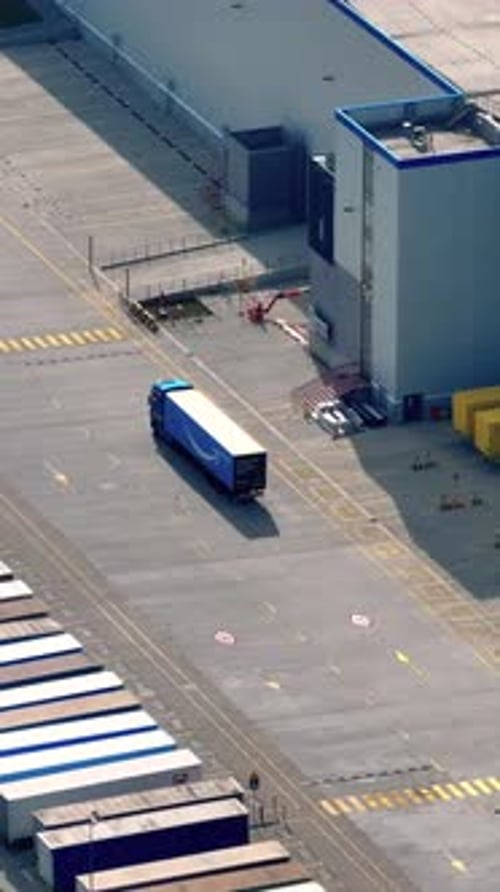 Aerial view of shipping yard with trucks and containers in commercial area