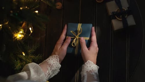 Woman Places Christmas Gift on Festive Table