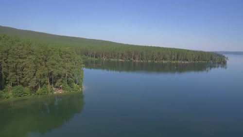 Um lago sereno cercado por uma floresta verde exuberante que o convida a explorar sua beleza