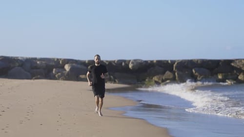 Young Athletic Man Running on the Beach Barefoot