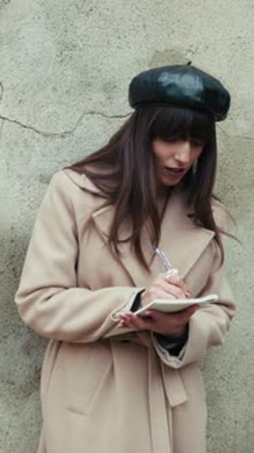 Woman with Beret Writes in Notebook Outdoors