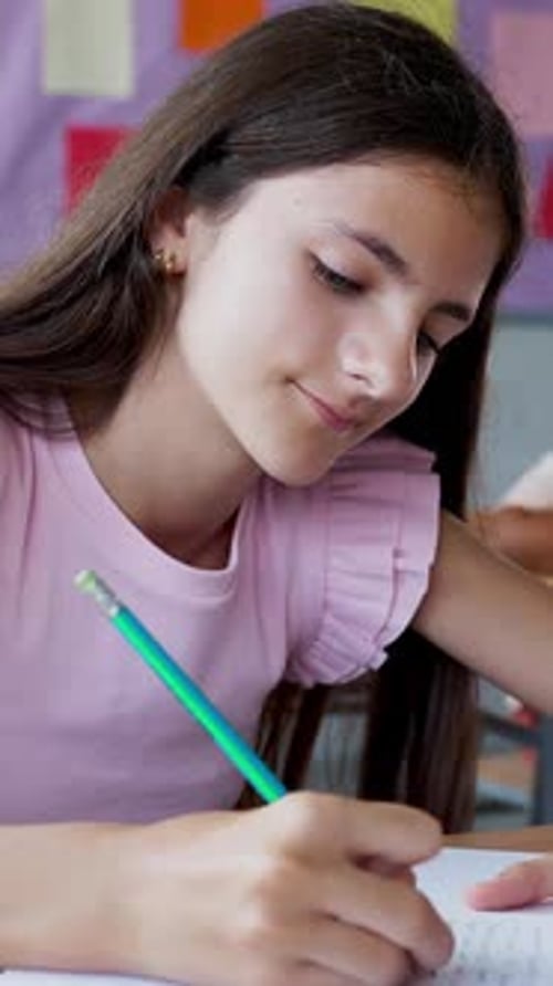 Young Student Girl Writing in Notebook While Studying at Primary School