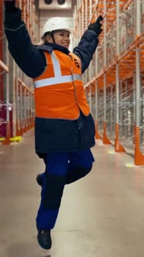 Vertical of Happy Female Engineer Runs and Jumps on Aisle Near Racks