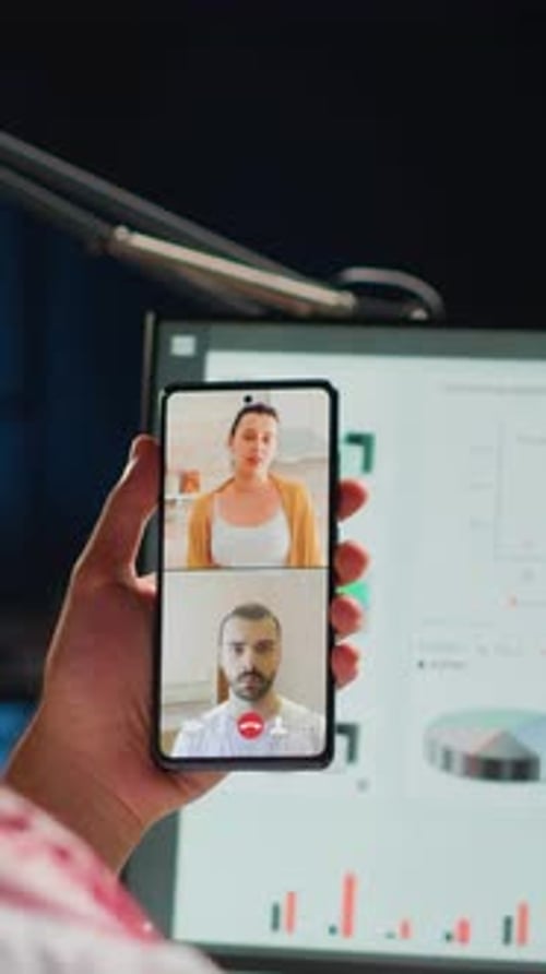 Man on Video Call Holding Smartphone in Dark Office