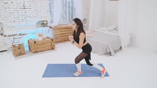 Beautiful girl in a black tracksuit is engaged in fitness at home. Fitness girl doing a squat, side