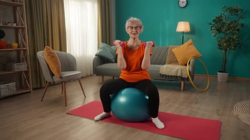 Senior Woman Exercising with Dumbbells on Exercise Ball