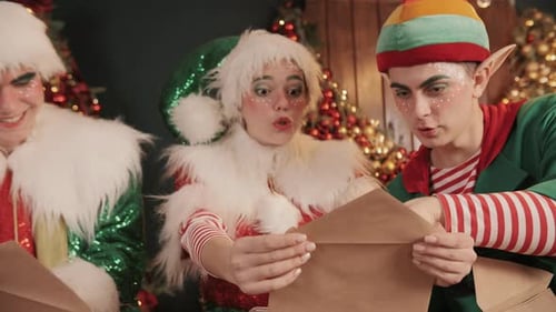Elves Reading Letters in Front of Christmas Tree