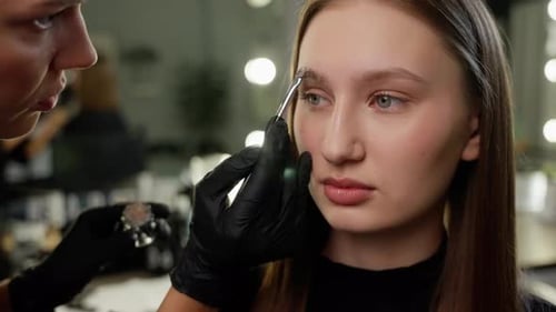 Makeup Artist Styling Young Woman's Eyebrows