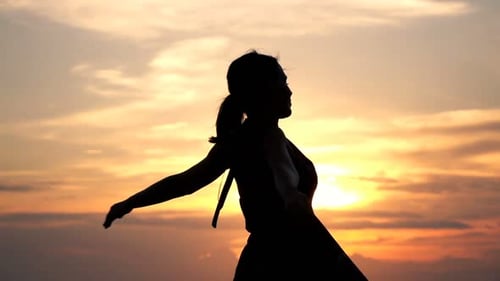Silhouette of Young Woman Stretching Arms at Sunset