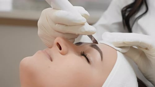 At a Beauty Clinic a Woman is Getting Eyebrow Microblading By a Skilled Artist with Precision The