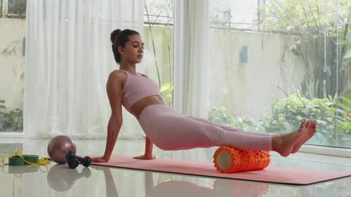 Woman Uses Foam Roller for Leg Exercise