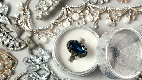 Background of many gold and silver jewelry and ring with blue gemstone in box