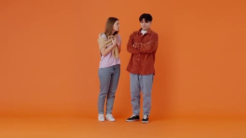 Une femme crie en gesticulant à un homme asiatique triste dans un studio lumineux