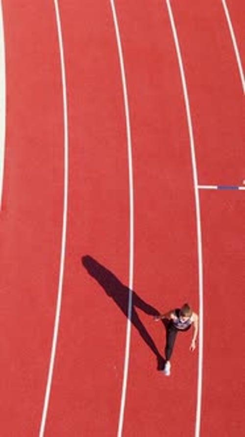Top Down View Of Young Woman Running On Red Stadium Track