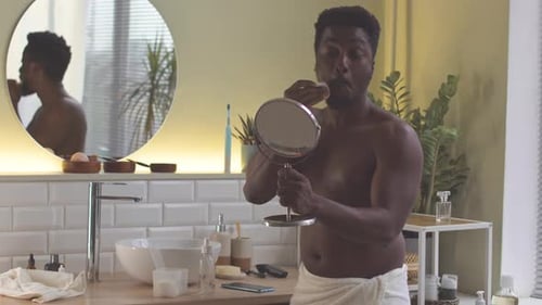 Man Cleans Face in Modern Bathroom