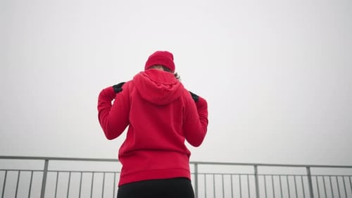 Back View of Woman Performing Hand Stretch and Head Turn Outdoors in Fitness Routine