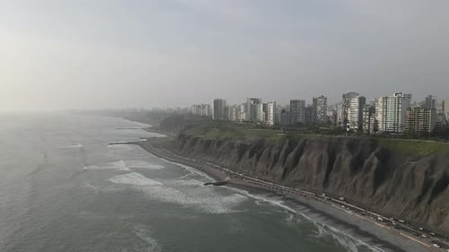 Vista aérea: La brumosa Lima Perú se eleva sobre la erosionada carretera de la playa de
