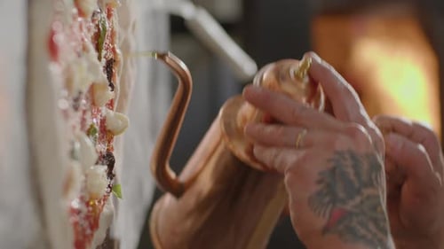 Chef Adding Oil to Pizza Before Baking