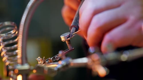 Close-up of the hands of a Caucasian man using a soldering tin iron while soldering some electrical