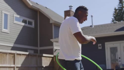 Father teaches children a fun hoop game in their sunny backyard in Canada