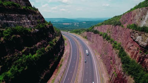 Beautiful aerial Dry van - reefer semi truck on a scenic highway between rocky hills, representing l