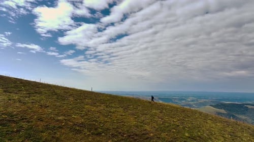 Aerial View of Solitary Hiker on Vast Green Slope