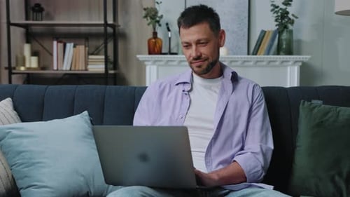 Man Works on Laptop While Sitting on Couch
