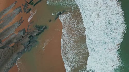 Foamy Waves Break Sandy Beach with Rocky Shoreline Top View Turquoise Sea Water