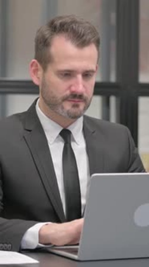 Man in Suit Working at Desk on Laptop