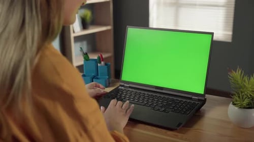 Woman Focused on Typing on a Laptop with Green Chroma Key Screen at a Home Office Desk Remote Work