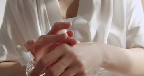 Person Applying Serum To Their Hand Indoors