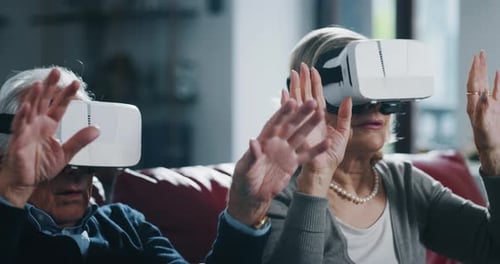 Close up of excited mature senior couple is having fun using vr glasses in living room at home.