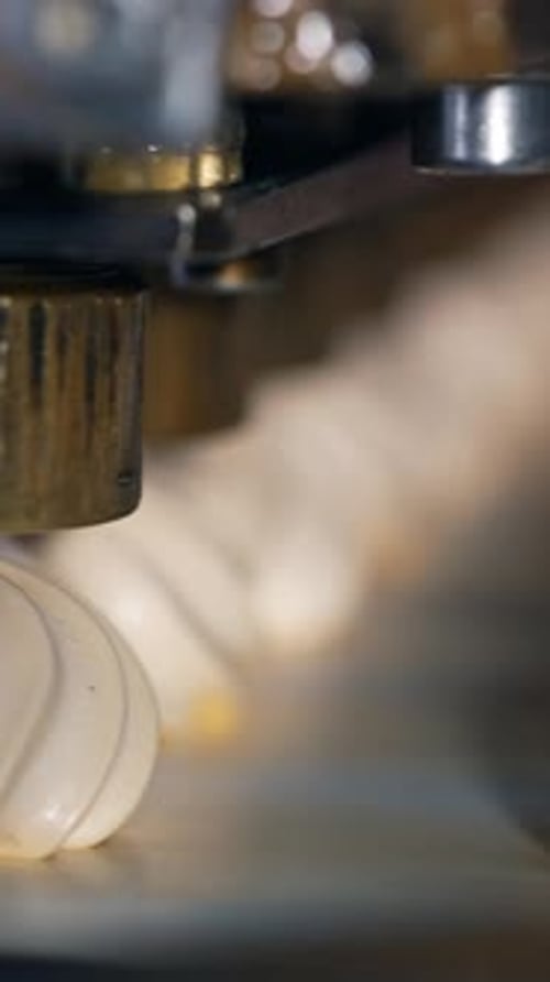 Whipped white vanilla cream comes out off a metal nozzle.