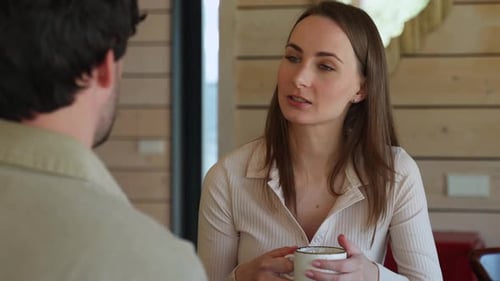 Woman Chatting with Man Indoors Holding Mug