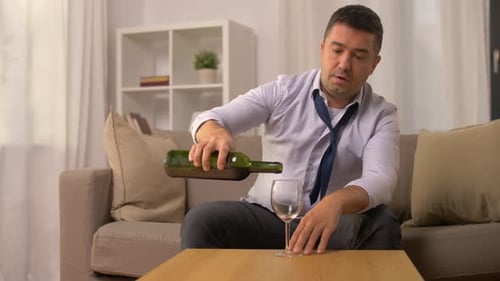 Lonely hispanic man with alcohol addiction pouring red port wine at home
